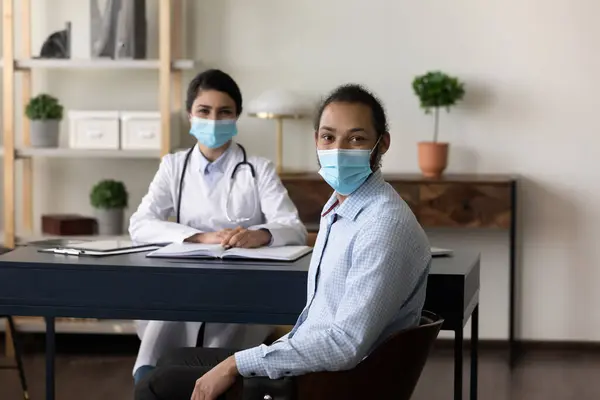 Felice multietnico medico femminile e paziente maschile indossando maschere per il viso — Foto Stock