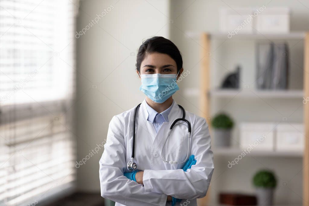Happy Indian female GP doctor in face mask, protective gloves