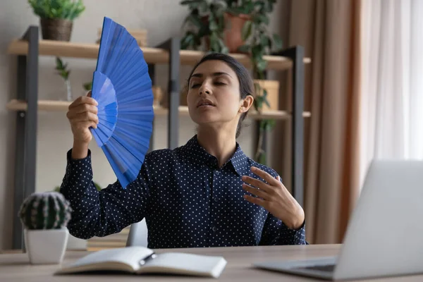 Přehřátá unavená indická obchodnice mávající papírovým ventilátorem na pracovišti — Stock fotografie