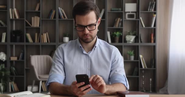 Glad ung manlig entreprenör som använder mobiltelefon på kontoret. — Stockvideo