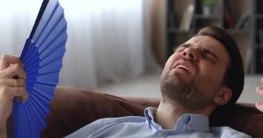 Yorgun genç adam evde aşırı ısınmış hissediyor..