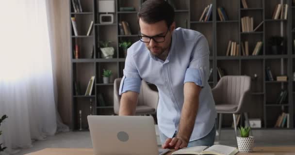 Jeune homme d'affaires concentré travaillant sur ordinateur debout à la table. — Video