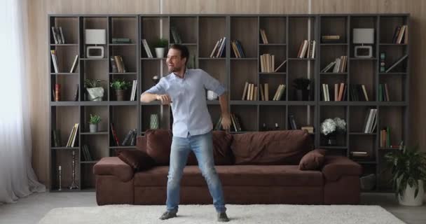Радісний молодий чоловік танцює в сучасній вітальні . — стокове відео