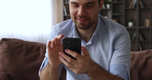 Uomo sorridente millenario che digita il messaggio nel cellulare. — Video Stock