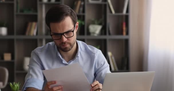 Fiatal üzletember, aki pénzügyi dokumentumokkal dolgozik az irodában. — Stock videók