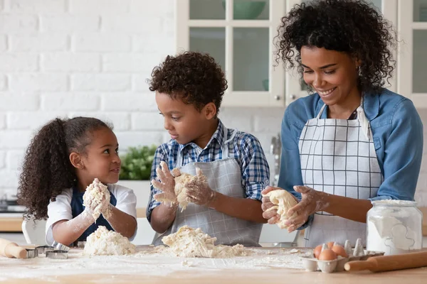 Happy African American mother with little kids kneading dough — Stock Photo, Image