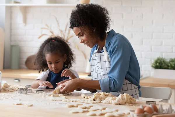 Glimlachende Afro-Amerikaanse moeder met kleine dochter koken koekjes — Stockfoto