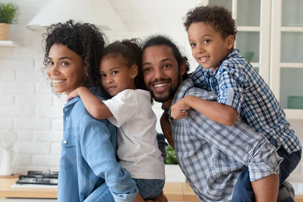 Πορτρέτο ευτυχισμένη Αφροαμερικανοί γονείς pigggy υποστήριξη δύο παιδιά — Φωτογραφία Αρχείου