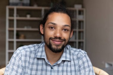 Fotoğraftaki yakışıklı Afrikalı Amerikalı adam kameraya bakıyor.