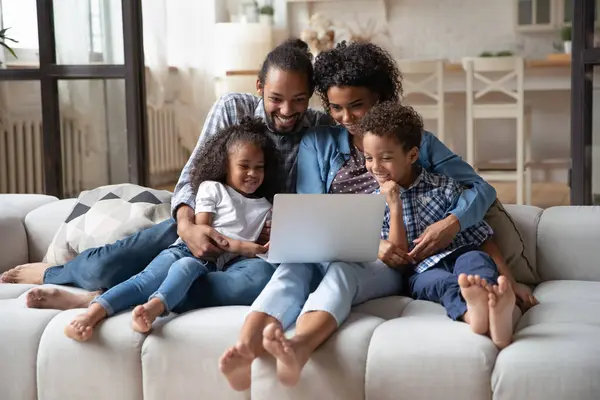 Heureux parents afro-américains avec des enfants utilisant un ordinateur portable ensemble — Photo