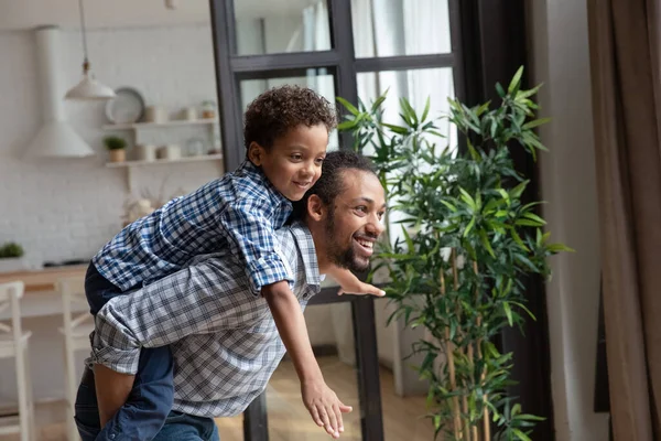 Sonriente afro-americano padre cerdito respaldo pequeño hijo, divertirse — Foto de Stock