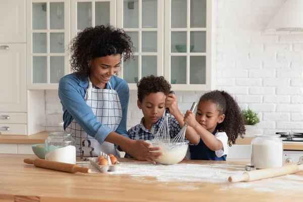 Zorgzame Afro-Amerikaanse moeder met kleine kinderen koken samen — Stockfoto