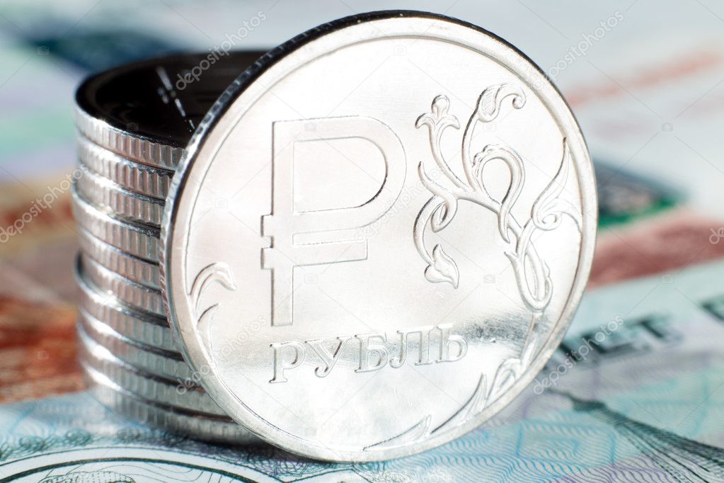 Several metal coins of one ruble standing on Russian paper banknotes