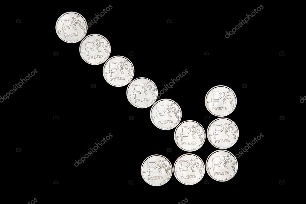 Several metal Russian ruble coins on black background form down arrow