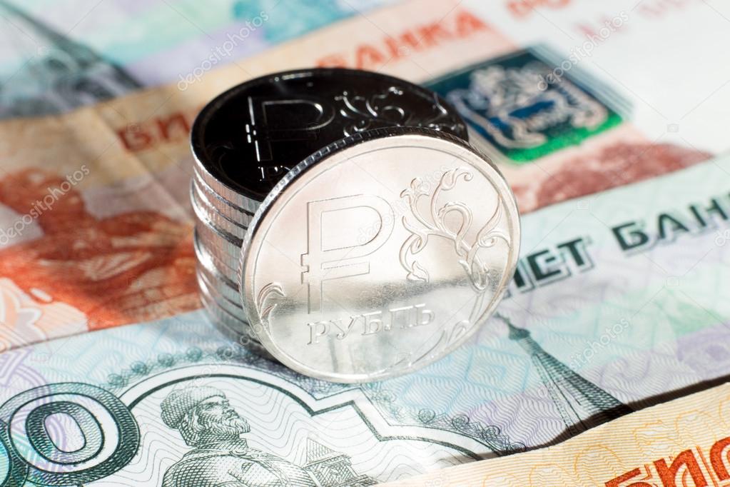 Several metal coins of one ruble standing on Russian paper banknotes