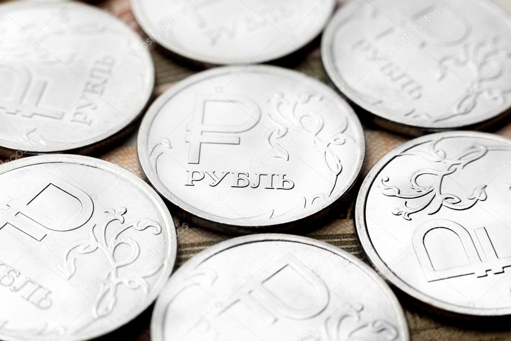 Several metal coins of value of one ruble that lie on Russian paper money