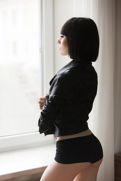 Sexy girl in leather jacket and shorts beside the window — Stock Photo, Image