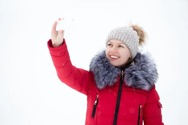 Szczęśliwy uśmiechający się kobieta w kurtka zimowa czerwony biorąc selfie, self-po — Zdjęcie stockowe