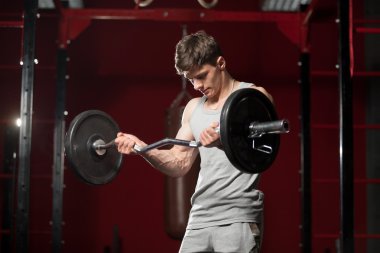 Genç adam spor salonunda ağırlık kaldırıyor
