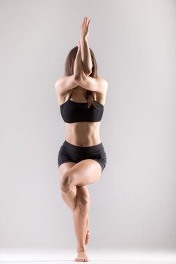 Yogi jimnastikçi kız Asana Garudasana, kartal poz yapıyor