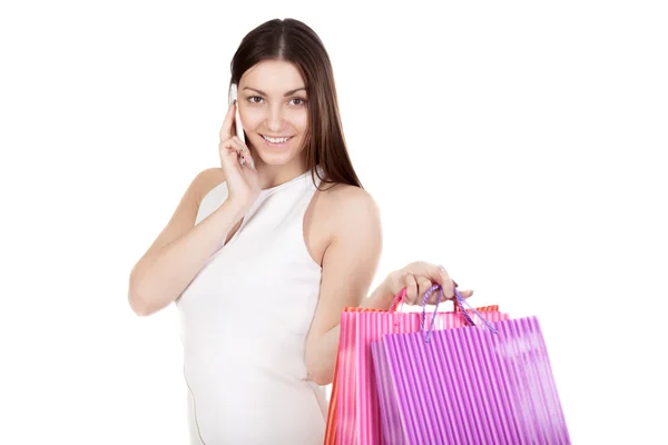 Smiling female using mobile phone holding with colorful shopping — Stock Photo, Image