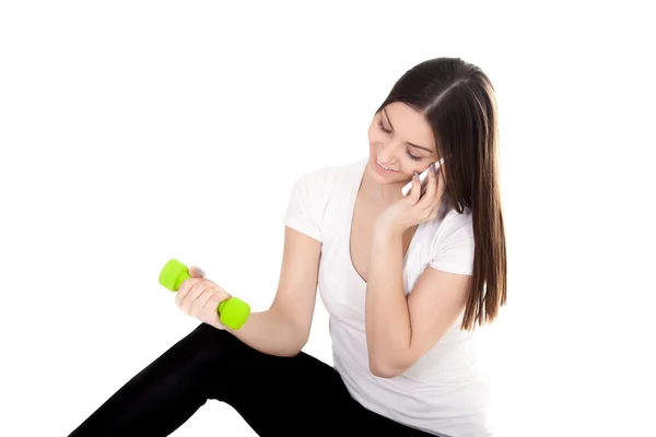 Smiling girl talking on phone and lifting dumbbells — Stock Photo, Image