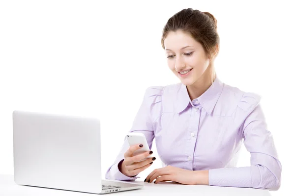 Giovane ragazza sms con smartphone davanti al computer portatile — Foto Stock