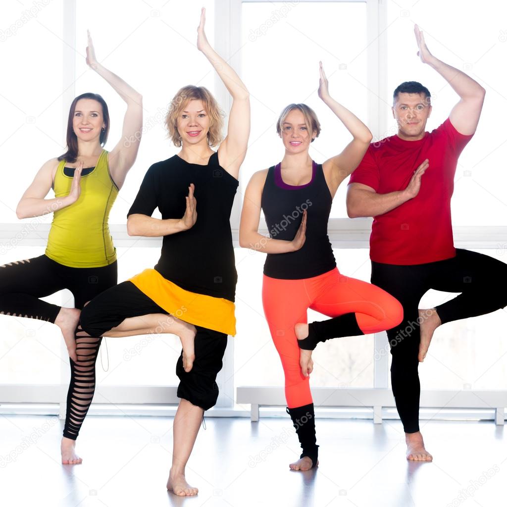 Group of happy people standing in yoga asana in class