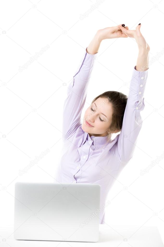 Tired young girl stretching in front of laptop