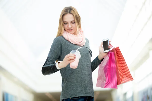 Young woman in supermarket checking time holding shopping bags, — Stock Photo, Image