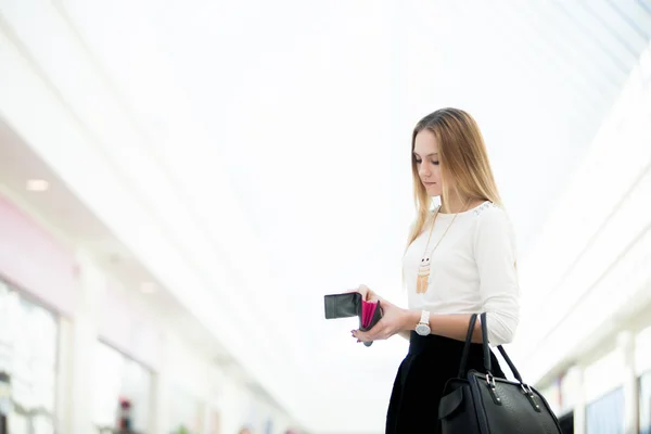 Young female standing with opened wallet in shopping mall — Stock Photo, Image