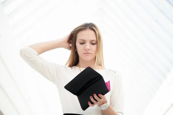 Mujer joven deprimida mirando en su bolso consternada — Foto de Stock