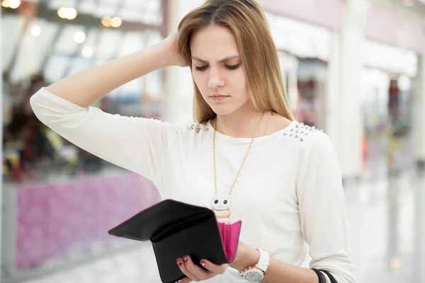 Mujer joven confundida revisando su bolso después de gastar demasiado — Foto de Stock