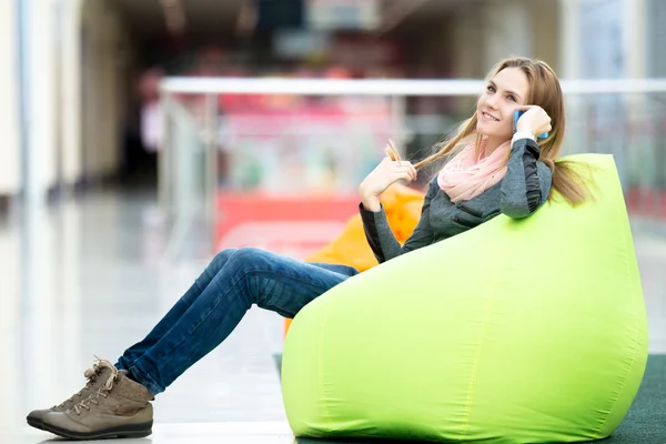 Улыбающаяся женщина сидит в бобовом мешке в офисе или торговом центре — стоковое фото