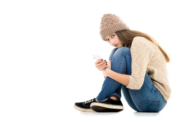 Teenage girl holding cell phone looking scared — Stock Photo, Image