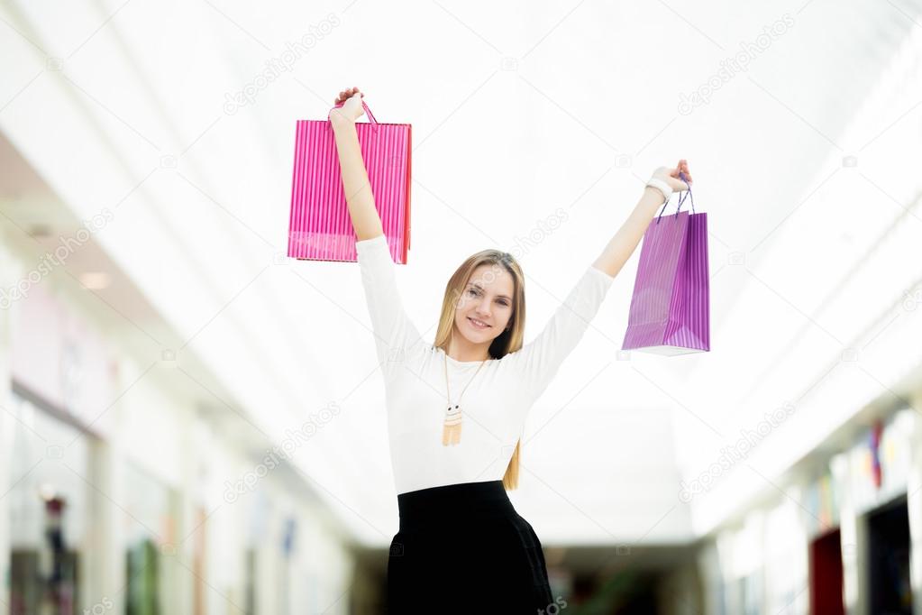 Smiling young woman holding up shopping bags with joy 
