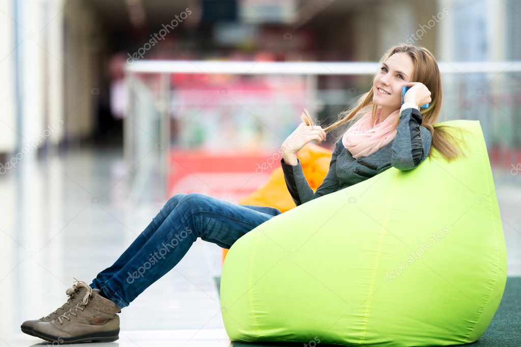 Smiling female sitting in bean bag in office or shopping center 