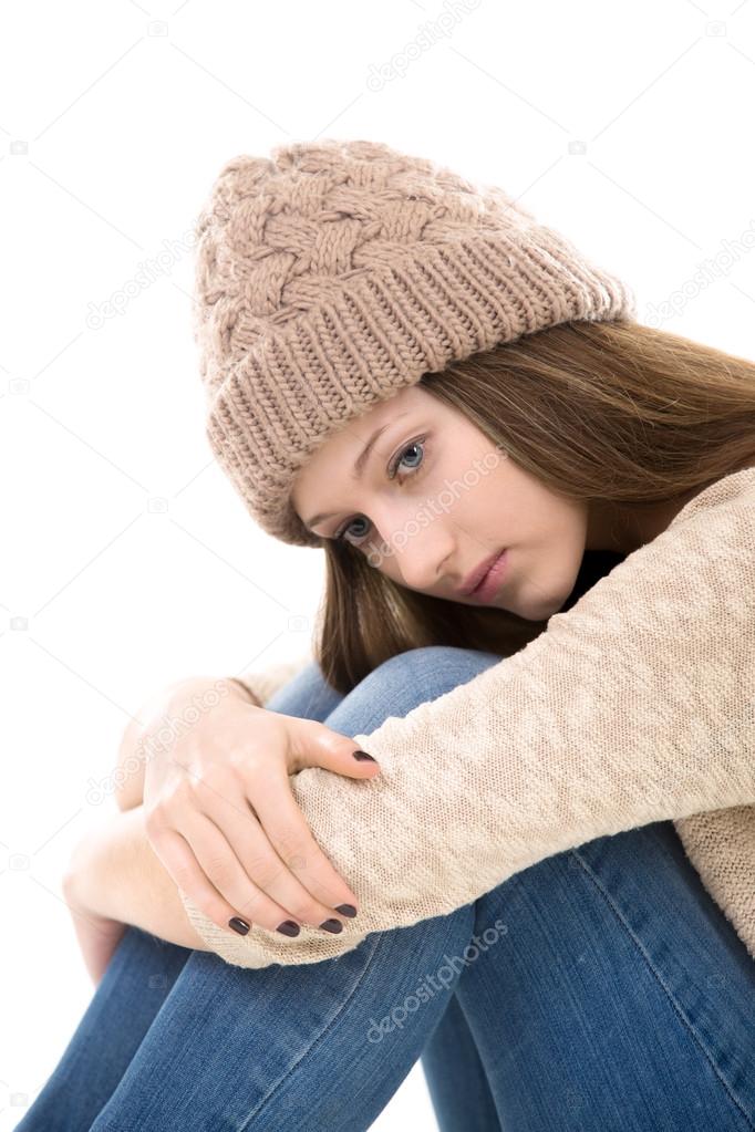 Sad teenage girl sitting embracing her knees 