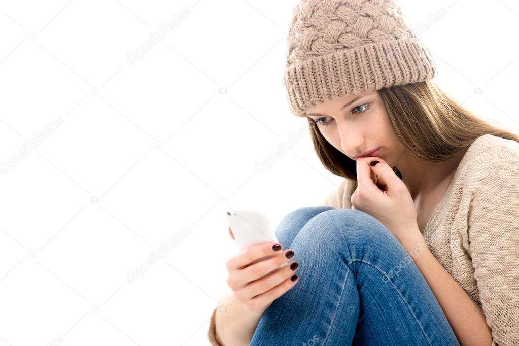 Upset teenage girl looking at her smartphone