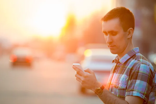 Jonge man met smartphone op zonnige street — Stockfoto