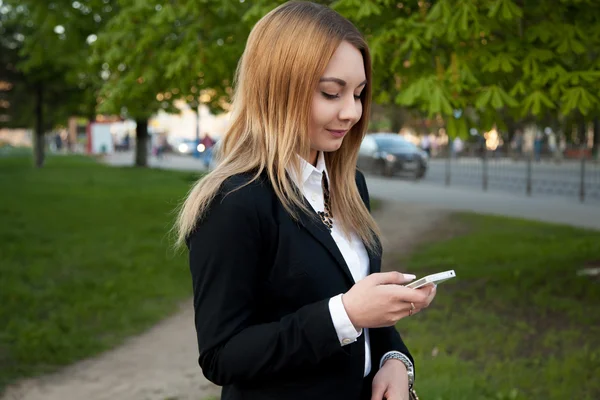 Ung kvinde med mobiltelefon i byen - Stock-foto