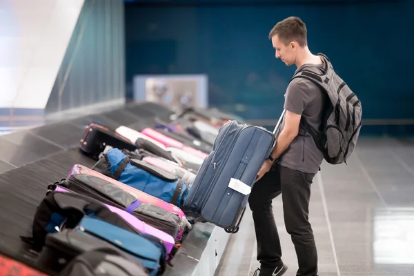 Young man collecting his luggage — Stock Photo, Image