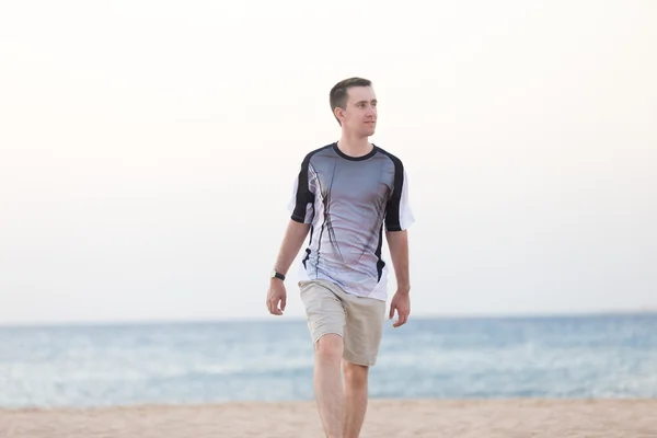 Young man walking on the beach — Stock Photo, Image