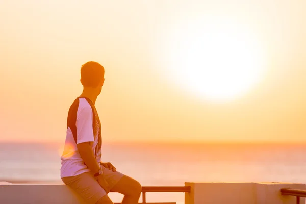 Jonge man genieten van uitzicht op zee vanaf het balkon — Stockfoto