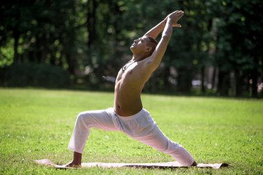 Warrior 1 yoga pose in park