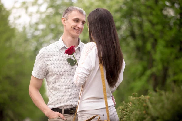 Smiling young man giving flower — Stock Photo, Image