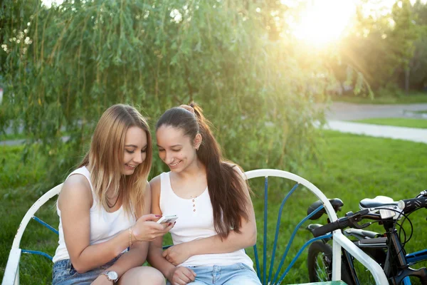 Cheerful teenage girls with cellphone in park — Stock Photo, Image