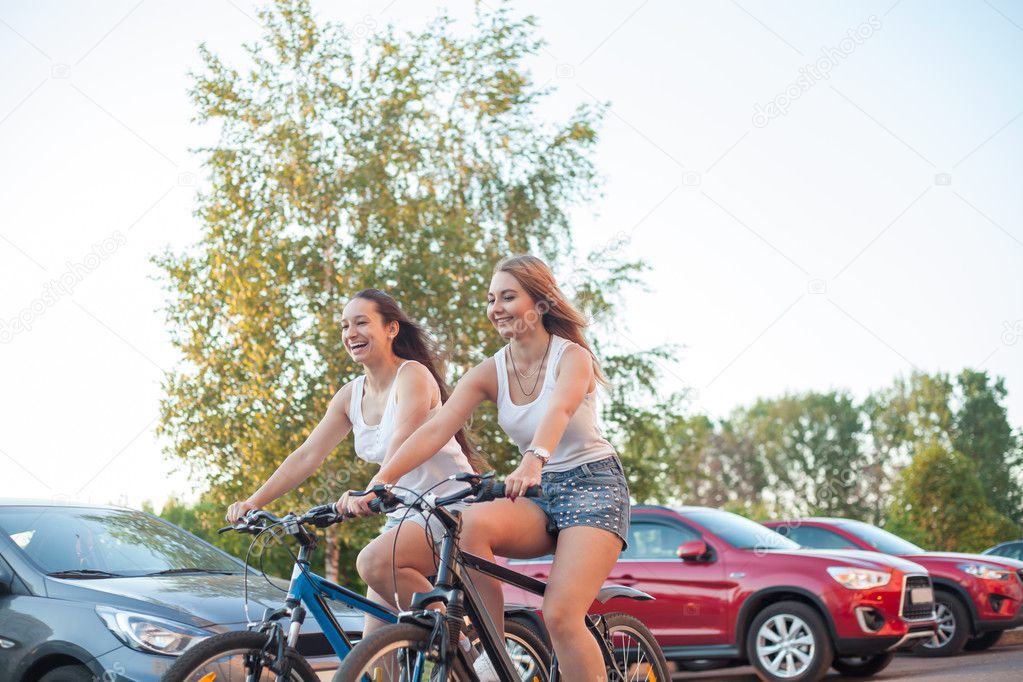 Smiling teenage girls racing on bicycles