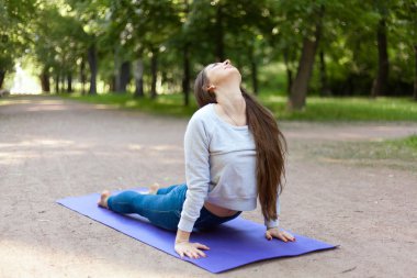 Upward facing dog pose in park alley