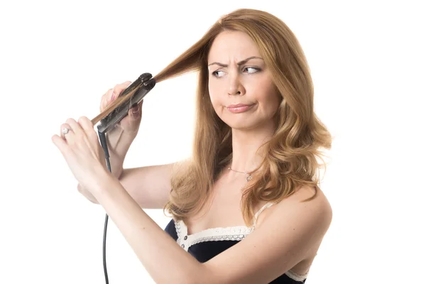 Young woman straightening frizzy hair — Stock Photo, Image